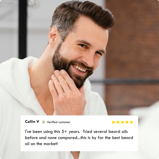 A smiling man with a well-groomed beard and mustache wears a white robe, with a customer review overlay at the bottom praising a beard oil.