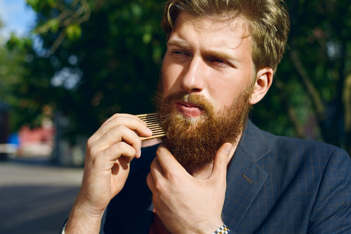 Man combing his short beard with a wood comb