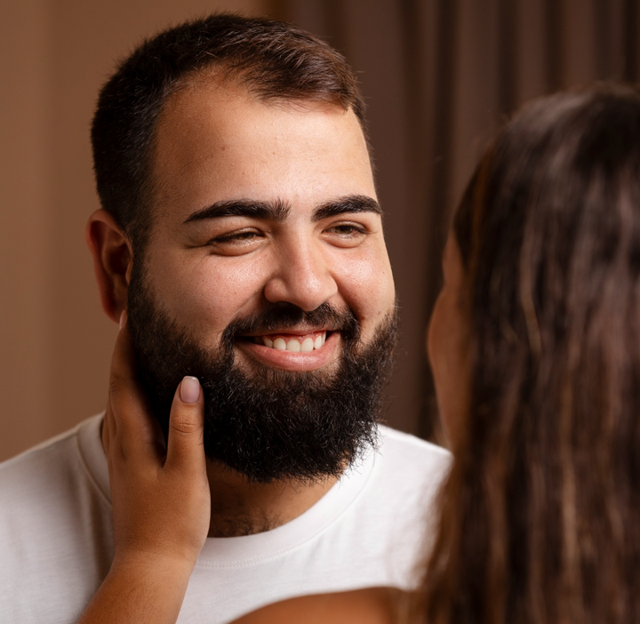 Woman gently touching the face of a smiling man with a short beard